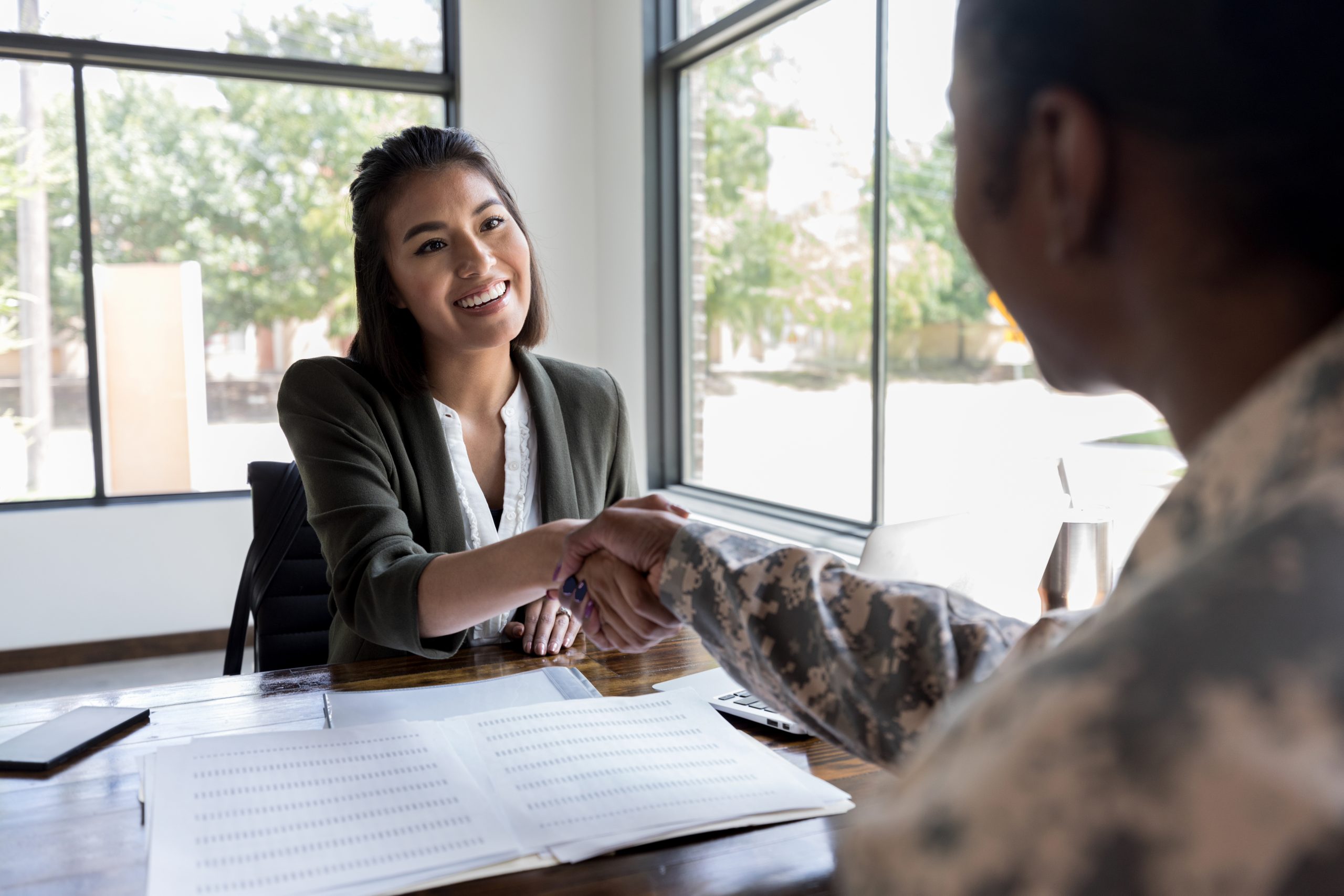 Financial advisor meets with veteran Smiling young female financial advisor greets female soldier.